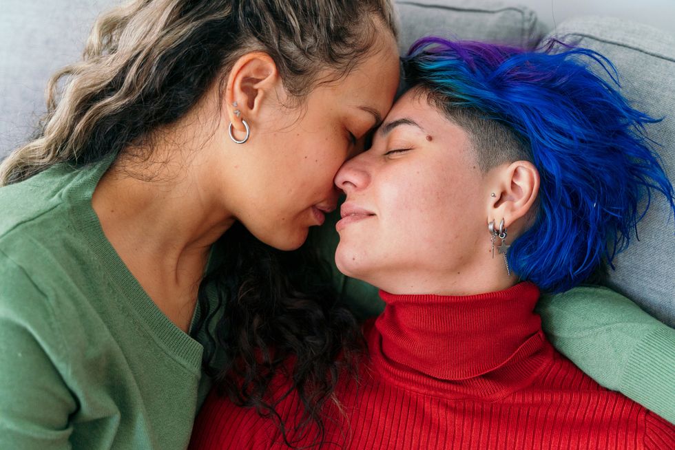 horizontal top view of hispanic young gay women kissing in the couch at home lgbt community lifestyle indoors