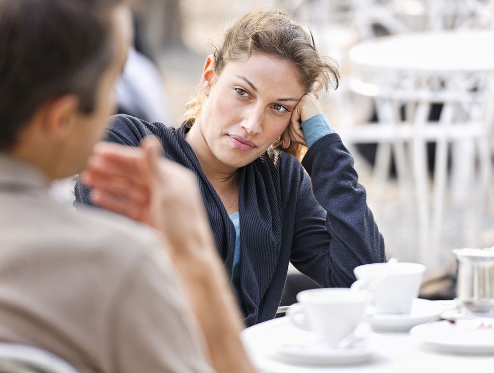 a woman listening to a man defocussed talking during a discussion at an outdoor cafe