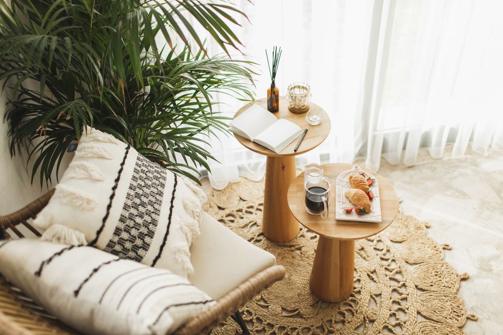 a lazy morning for yourself, have a coffee with a croissant, writing down goals to achieve in notepad or making to do list, writing diary wicker furniture with eco materials, handicraft cushions, aroma reed diffuser and textile at boho chic interior hygge and aromatherapy concept