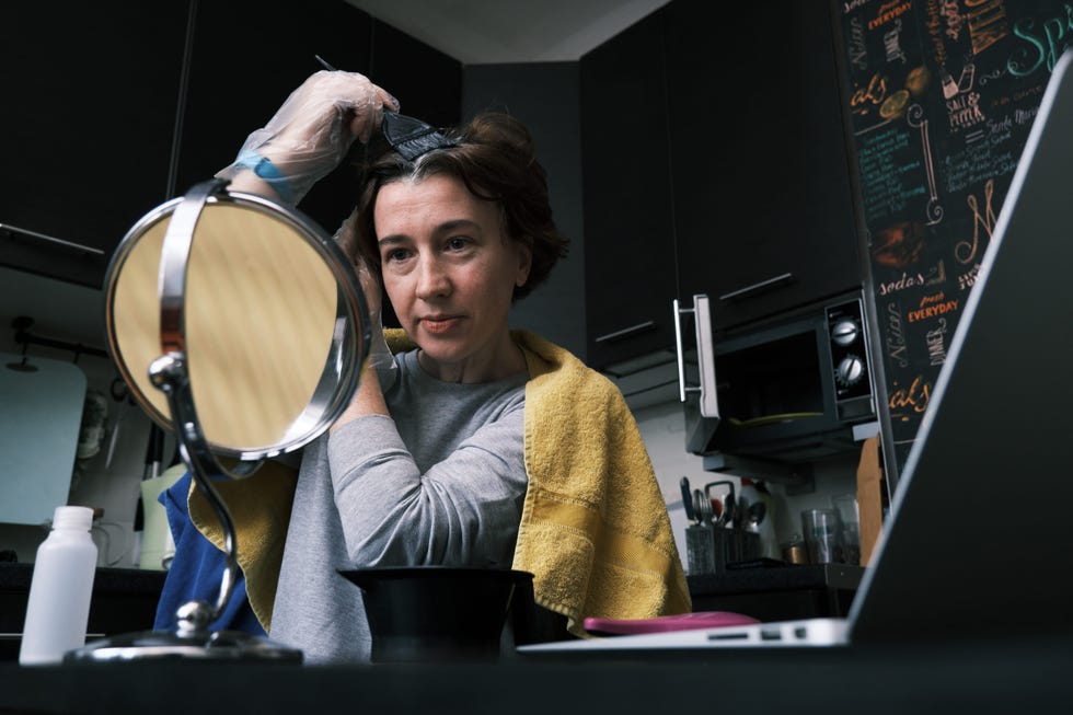 woman applying hair dye in a kitchen