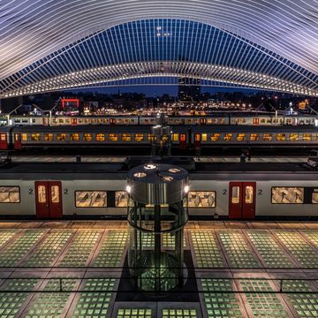 a beautiful shot of a train station in belgium with lights at night time