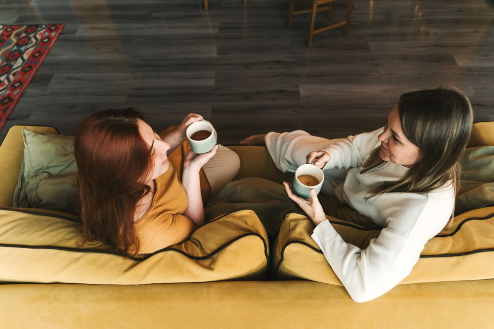 two women are sitting and talking woman psychologist practicing with patient women coach session between girlfriends therapists gestures female talking and drinking a cup of tea