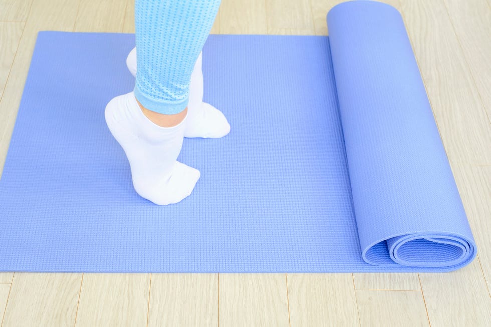 female legs doing exercises lifting on toes close up on blue background