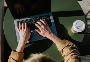 corporate image of hands typing on a laptop keyboard in an outdoor environment, perhaps a balcony, a garden or a rooftop terrace