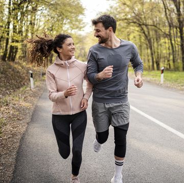 happy athletic couple having fun while running in spring day