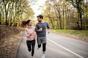 happy athletic couple having fun while running in spring day