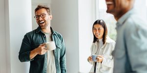 business people laughing together during a coffee break at work group of young professionals standing together in an office