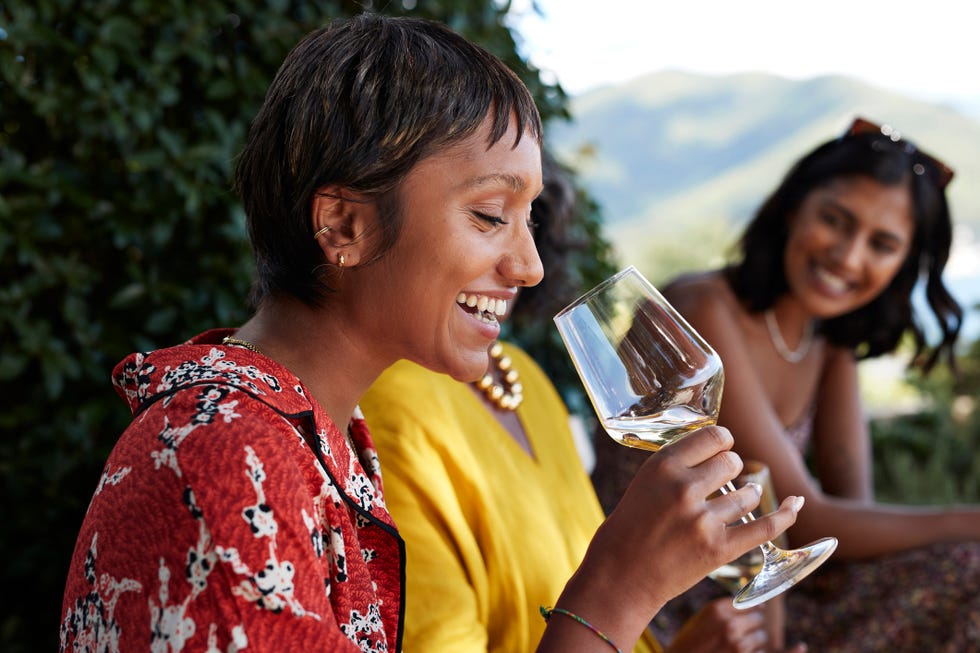 happy young woman with short hair having white wine by friends