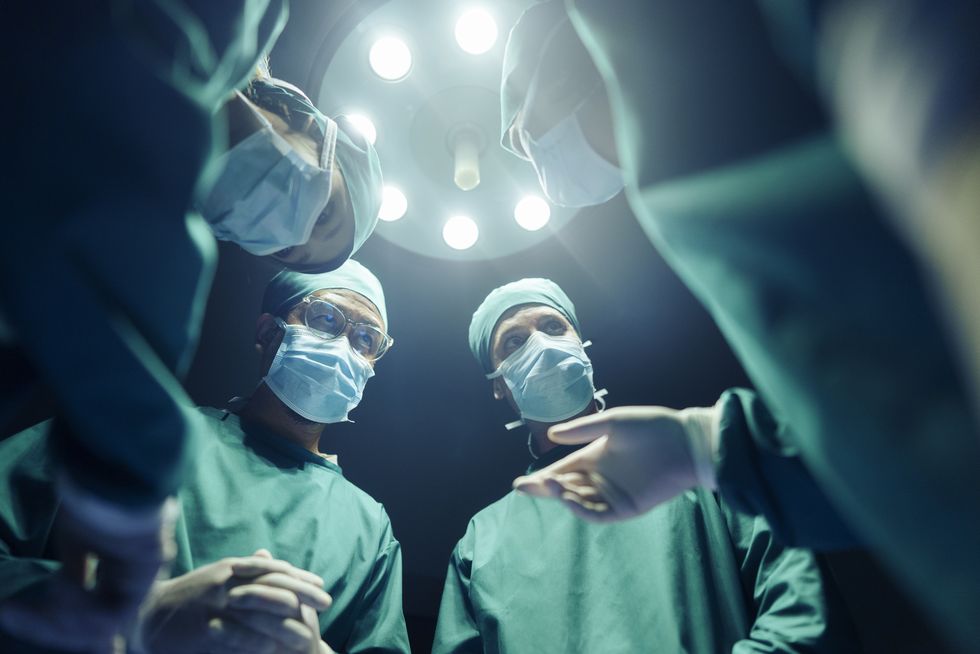 four surgeons stand together in operating room