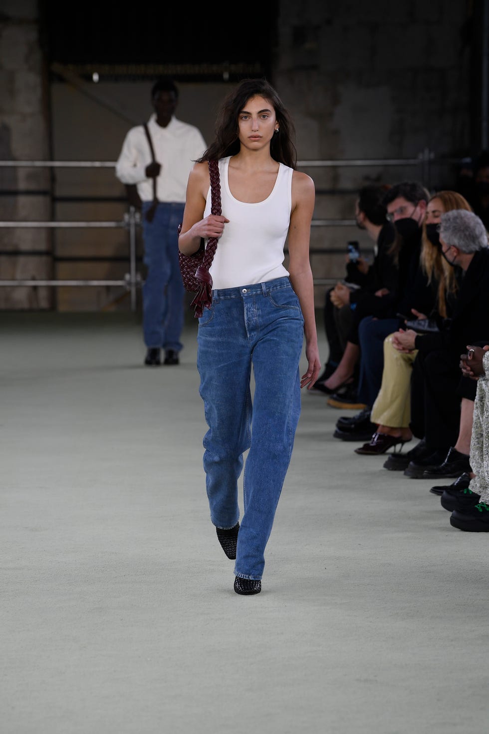 model paola manes walks the runway in a nubuck leather white tank top, denim jeans and the kalmimero intrecciato woven leather bag from bottega veneta's fall 2022 ready to wear collection shown in milan photo by giovanni giannoniwwdpenske media via getty images