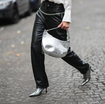 paris, france december 03 natalia verza wears a white silk buttoned shirt, a silver shiny varnished leather shoulder bag, black shiny leather large wide legs pants, a silver chain belt, black with embroidered silver sequined pointed heels ankle shoes , bracelet, during a street style fashion photo session, on december 03, 2022 in paris, france photo by edward berthelotgetty images