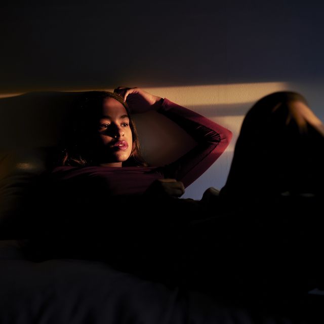woman lying in bed between lights and shadows