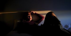 woman lying in bed between lights and shadows
