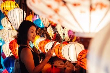 young female traveller with mobile phone exploring local market at night in vietnam during chinese new year solo traveller travel like a local