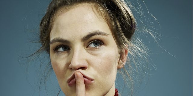 A young hip woman with her index finger on her lips, thinking