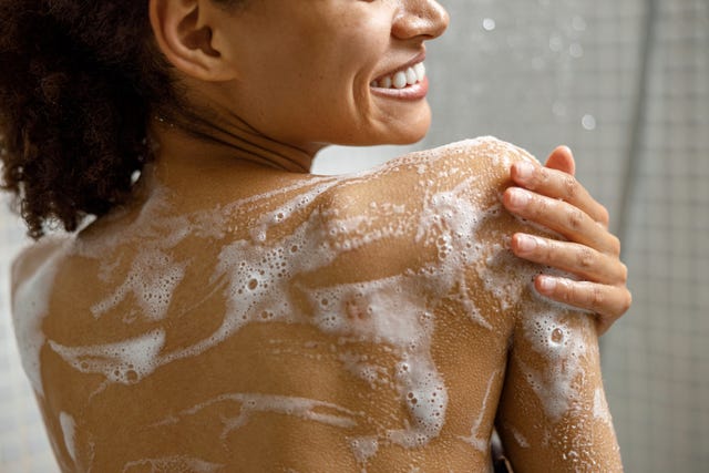 close up of african woman taking a shower with gel or shampoo foam in bathroom high quality photo