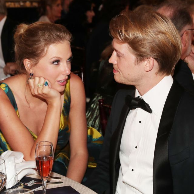 taylor swift looking at joe alwyn while they're seated together at a table