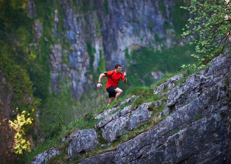 extreme male runner running up steep incline wearing hi visibility top