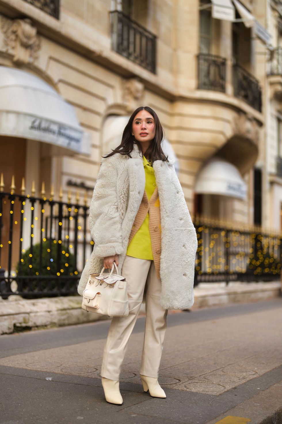 woman in white fur coat with white bag, pants, and boots