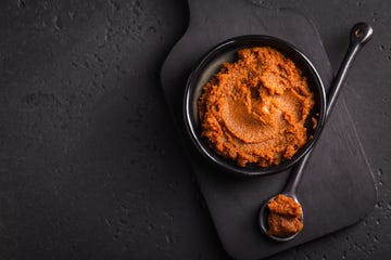 miso in a black bowl and on a black spoon, all on a black cutting board