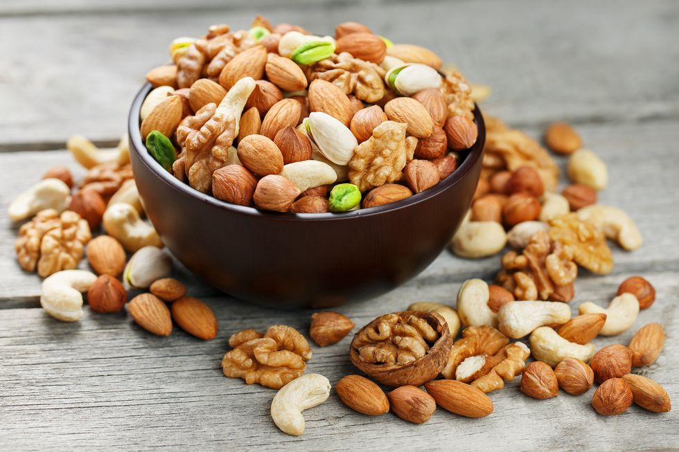 wooden bowl with mixed nuts on a wooden gray background healthy food and snacks, organic vegetarian meals walnut, pistachios, almonds, hazelnuts and cashews, walnut