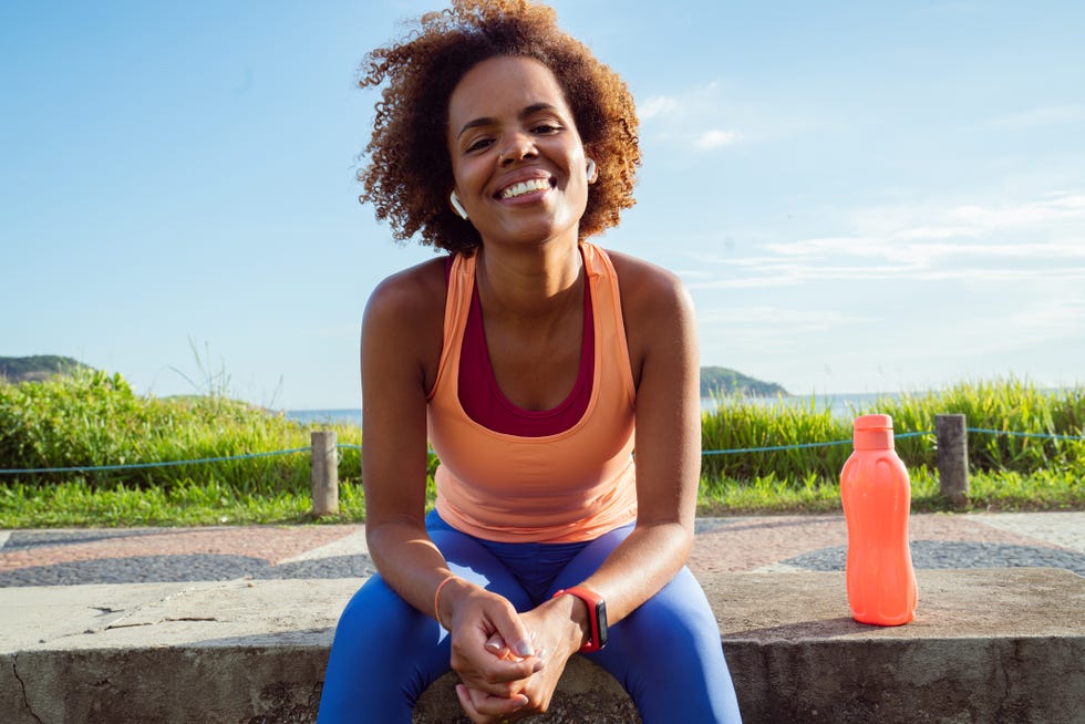 a young brazilian female runner having refreshment while exercise outdoors