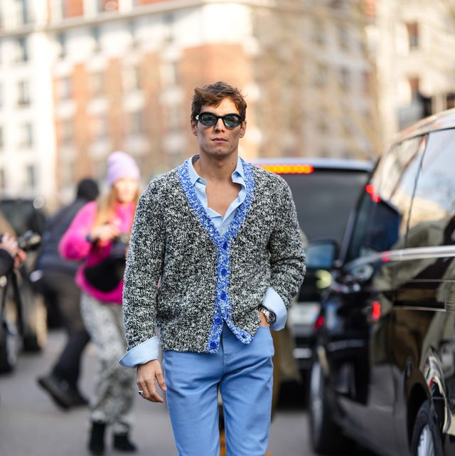 paris, france january 21 a guest wears black sunglasses, a pale blue shirt, a black and white print pattern with blue wool borders buttoned cardigan, blue suit pants, white sneakers, a silver watch , outside loewe, during paris fashion week menswear fall winter 2023 2024, on january 21, 2023 in paris, france photo by edward berthelotgetty images