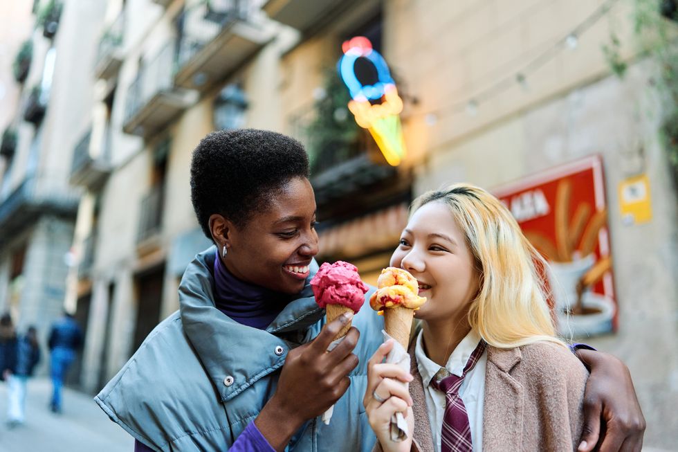 romantic scene of a multiethnic lesbian couple eating an ice cream together in the street in barcelona