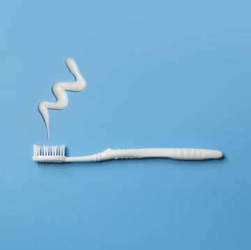 close up view of one flat lay white toothbrush and tooth paste on blue background