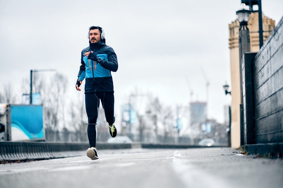 mid adult sportsman jogging outdoors on rainy day copy space