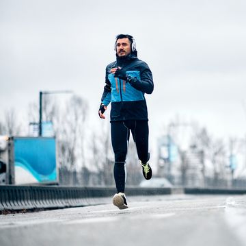 mid adult sportsman jogging outdoors on rainy day copy space