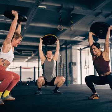 group of strong and active male and female athlete exercise together at the gym, while lifting weights