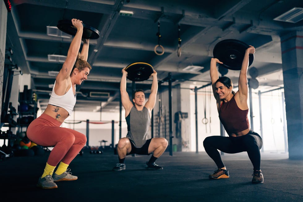 group of strong and active male and female athlete exercise together at the gym, while lifting weights