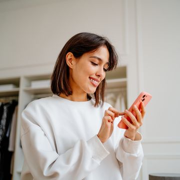 smiling businesswoman checking orders by smartphone in clothes shop