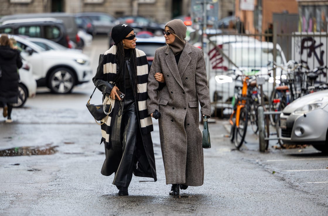 copenhagen, denmark january 31 amaka hamelijnck wears black white striped scarf, prada bag, celine beanie, black coat, leather pants benthe liem wears brown balaclava, grey tailored coat, green bag outside rabens saloner during the copenhagen fashion week autumnwinter 2023 on january 31, 2023 in copenhagen, denmark photo by christian vieriggetty images