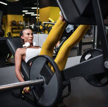 vrouw in gele sportlegging op leg press machine