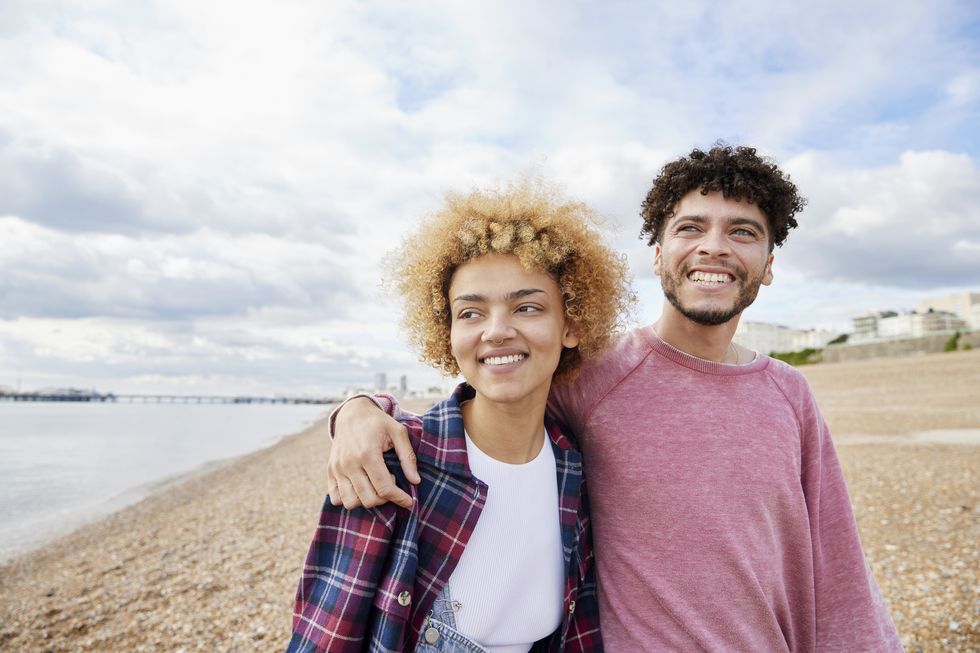 young smiling couple in their 20s embracing on beach, brighton, united kingdom