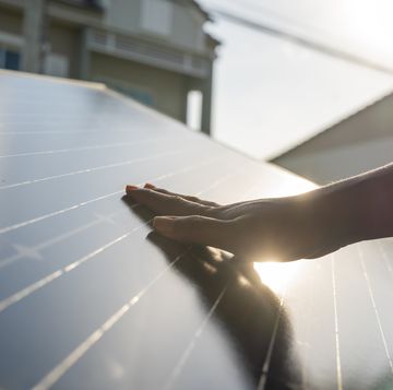 human hand touching solar panel mounted at home
