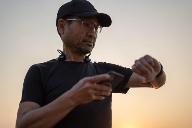 een sportende man kijkt op zijn hardloophorloge