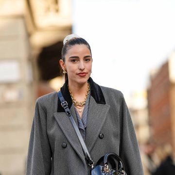 milan, italy february 25 bettina looney wears a beige ribbed velvet hair elastic, gold earrings, a gold large chain and diamonds necklace, a gray striped print pattern with black velvet collar long coat, a black shiny varnished leather lady d light crossbody bag from dior, outside bally, during the milan fashion week womenswear fallwinter 20232024 on february 25, 2023 in milan, italy photo by edward berthelotgetty images