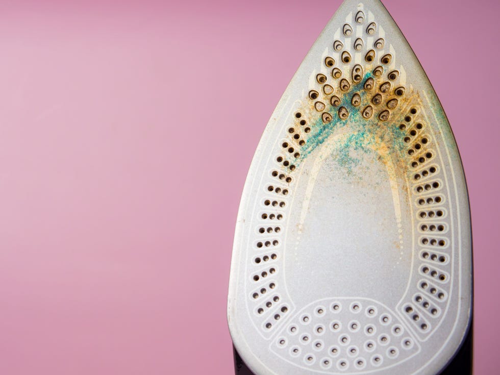 a closeup view of the soleplate of a clothing iron showing signs of residue and discoloration