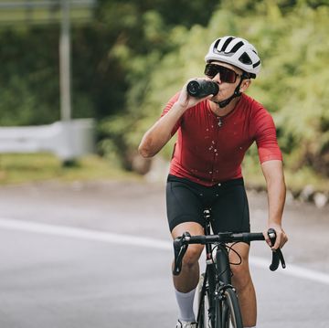 asian chinese professional cyclist athlete drinking water during cycling
