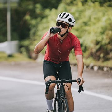 asian chinese professional cyclist athlete drinking water during cycling
