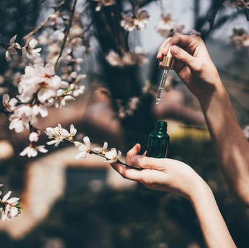 Hand with pipette at spring flowers on background. hand with pipette at spring flowers on background