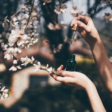 hand with pipette at spring flowers on background