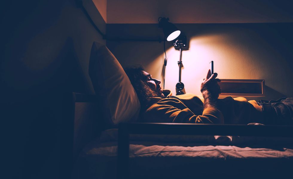 man using smart phone in bed at night