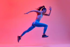 dynamic portrait of young active girl, athlete, runner in motion, training over pink studio background in neon light concept of sportive lifestyle, health, endurance, action and motion ad