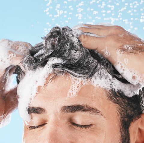 face, water splash and shampoo shower of man in studio isolated on a blue background water drops, hair care and male model washing, bathing or cleaning for healthy skin, wellness or skincare hygiene