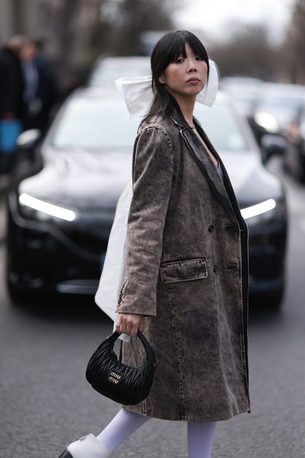 A person in a stylish outfit holding a handbag walking on a street