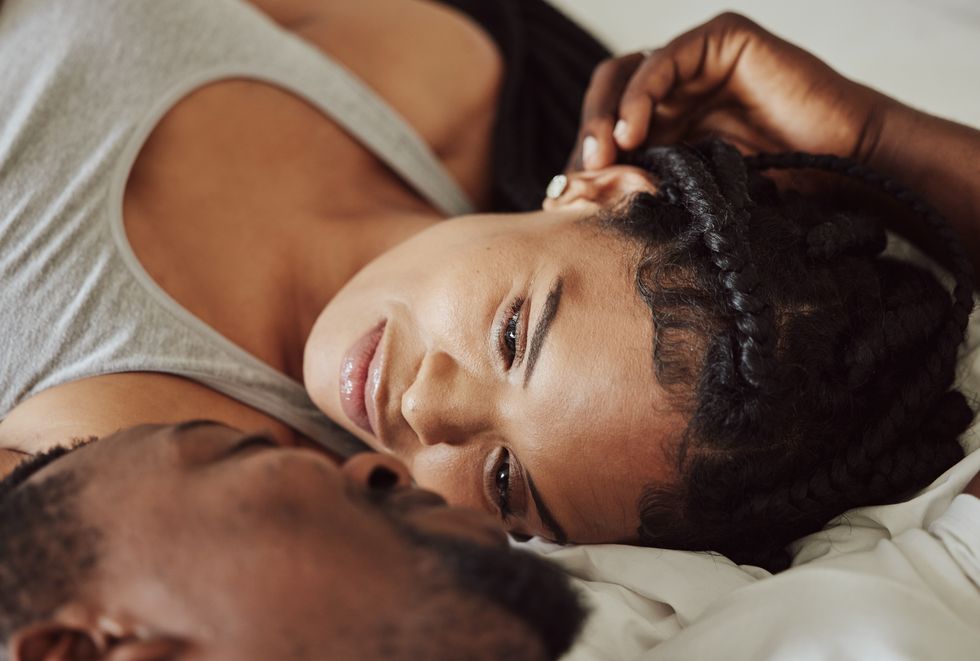 black couple, love and bedroom romance while happy and intimate on a bed at home, apartment or hotel to relax face of a young man and woman in a happy marriage with commitment, trust and care